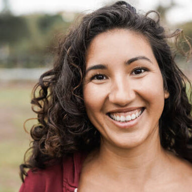 Hispanic girl smiling on camera outdoor in city park - Focus on face